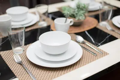 a table with white plates and glasses and silverware at Binjai 8 KLCC by PSM Luxury Suites in Kuala Lumpur