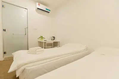 a white room with two beds and a table at Fumah Hotel Jalan Kuching in Kuala Lumpur