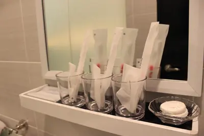 a shelf with four glass cups on it in a bathroom at BIG M Hotel in Kuala Lumpur