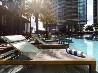 a pool with chaise lounges and volleyballs at Sofitel Kuala Lumpur Damansara in Kuala Lumpur