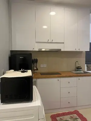 a kitchen with white cabinets and a microwave at Parkview Suite KLCC, Bernice in Kuala Lumpur