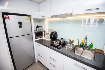 a kitchen with a white refrigerator and a sink at KL Sentral Bangsar Suites EST BY PSM LUXURY SUITES in Kuala Lumpur