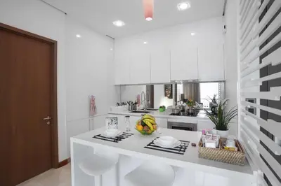 a white kitchen with a counter with two white stools at Soho Suites KLCC by 21 Century travel in Kuala Lumpur