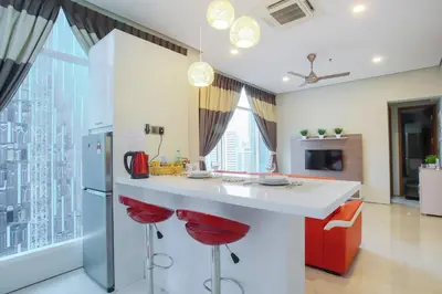 a kitchen with a white counter and red stools at Soho Suites KLCC by 21 Century travel in Kuala Lumpur