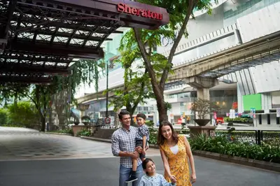 a family posing for a picture in front of a building at Sheraton Imperial Kuala Lumpur Hotel in Kuala Lumpur