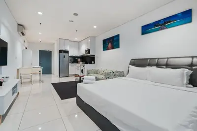 a white bedroom with a large bed and a kitchen at Summer Suites KLCC Apartments by soulasia in Kuala Lumpur