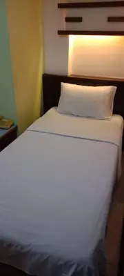 a bedroom with a white bed with a light on it at Hotel China Town 2 in Kuala Lumpur