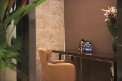 a table in a room with a chair and flowers at Dorsett Kuala Lumpur in Kuala Lumpur