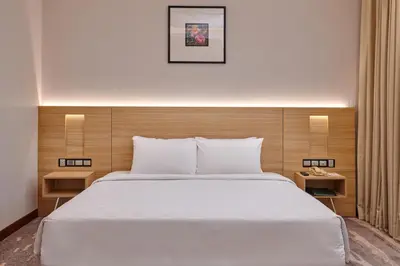 a bedroom with a large white bed with a wooden headboard at Cititel Mid Valley in Kuala Lumpur