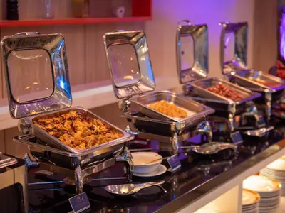 a buffet with several trays of food on a counter at Hotel Royal Kuala Lumpur in Kuala Lumpur