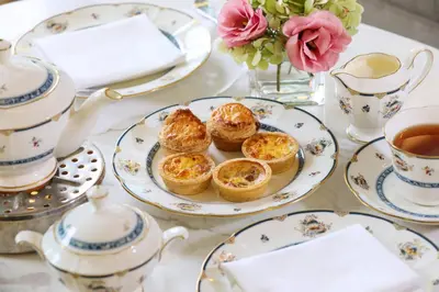 a table with plates of pastries and cups of tea at The Ritz-Carlton, Kuala Lumpur in Kuala Lumpur