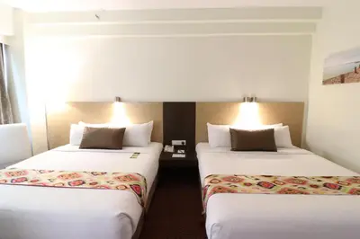 two beds in a hotel room with white sheets at Hotel Grand Continental Kuala Lumpur in Kuala Lumpur