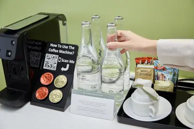 a person holding a bottle of water next to a coffee maker at Sunway Velocity Hotel Kuala Lumpur in Kuala Lumpur
