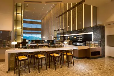a restaurant with a bar with yellow stools at Hilton Kuala Lumpur in Kuala Lumpur