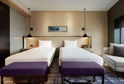 a hotel room with two beds and a couch at Hilton Kuala Lumpur in Kuala Lumpur