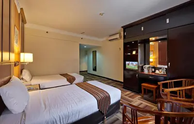 a hotel room with two beds and a television at Palace Hotel in Kuala Lumpur