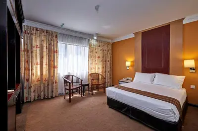 a hotel room with a bed and a table and chairs at Palace Hotel in Kuala Lumpur