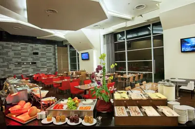 a dining room with tables and red chairs and food at PARKROYAL Serviced Suites Kuala Lumpur in Kuala Lumpur