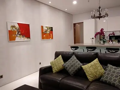 a living room with a brown couch and a kitchen at Soho Suites KLCC by LX Suites in Kuala Lumpur