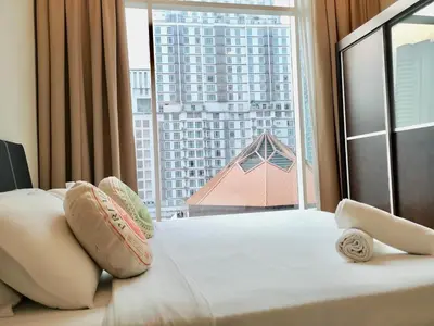a bed with pillows and a large window with a building at Soho Suites Klcc By Pnut KLCC VIEW in Kuala Lumpur