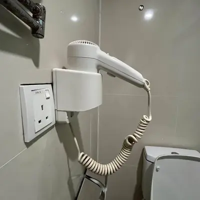 a white blow dryer in a bathroom next to a toilet at Frenz Hotel Kuala Lumpur in Kuala Lumpur