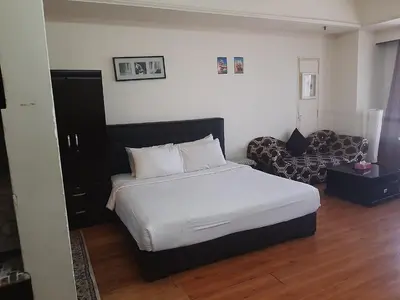 a bedroom with a white bed and a couch at Genius Service Suites at time square kl in Kuala Lumpur
