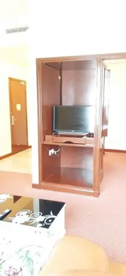a living room with a tv in a cabinet at Genius Service Suites at time square kl in Kuala Lumpur
