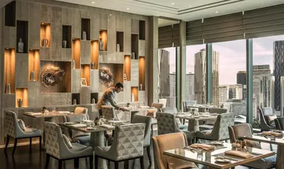 a restaurant with tables and chairs with a view of the city at Four Seasons Hotel Kuala Lumpur in Kuala Lumpur