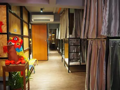 a corridor of a room with bunk beds and a parrot on a table at Leo Backpackers @ Central Market in Kuala Lumpur