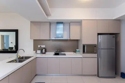a kitchen with white cabinets and a stainless steel refrigerator at Holiday Heaven in Kuala Lumpur
