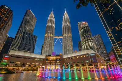 a fountain in front of the petronas towers at night at Inspired Homes @ KLCC Soho Suite in Kuala Lumpur
