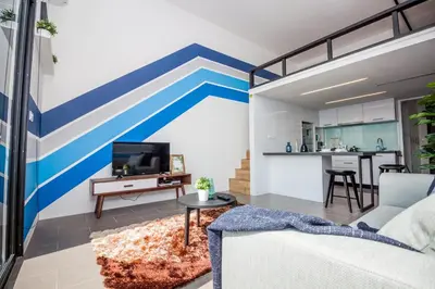 a living room with a blue and white striped wall at The Establishment KL Sentral Bangsar by Plush in Kuala Lumpur