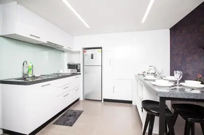 a kitchen with white cabinets and a table with chairs at The Establishment KL Sentral Bangsar by Plush in Kuala Lumpur