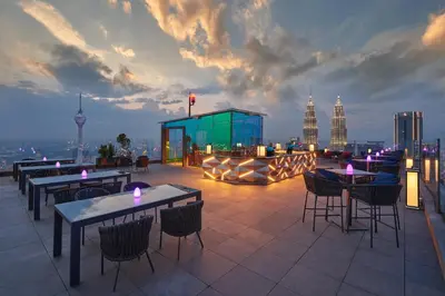 a rooftop patio with tables and chairs and a city skyline at Banyan Tree Kuala Lumpur in Kuala Lumpur