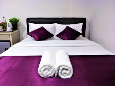 a bed with white towels and purple sheets at CITI HOTEL @ KL SENTRAL in Kuala Lumpur
