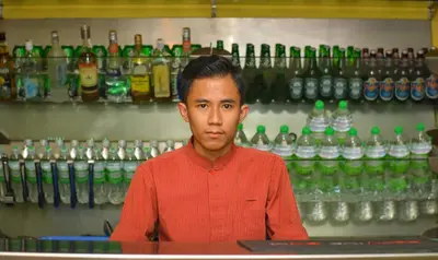 a man sitting at a counter in front of bottles at The Maple Suite in Kuala Lumpur