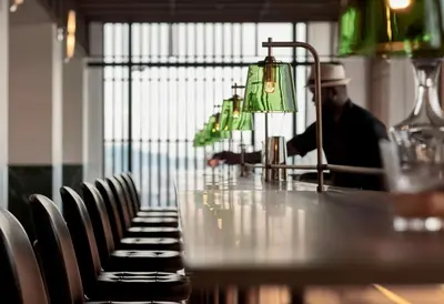 a man sitting at a bar with a table and chairs at Alila Bangsar Kuala Lumpur in Kuala Lumpur