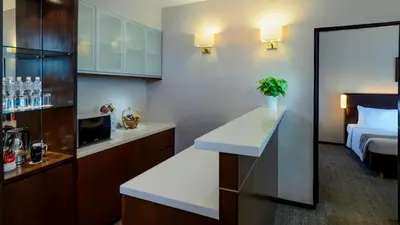 a hotel room with a bedroom with a bed and a kitchen at Furama Bukit Bintang, Kuala Lumpur in Kuala Lumpur