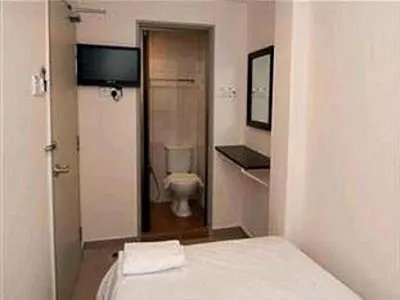 a bathroom with a toilet and a bed in a room at Hotel A-One in Kuala Lumpur