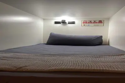a bedroom with a bed with a blue pillow at OYO 91036 J CAPSULE HOTEL @ JALAN BUKIT BINTANG in Kuala Lumpur