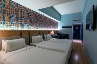 a bedroom with two beds and a brick wall at ibis Styles Kuala Lumpur Bukit Bintang in Kuala Lumpur