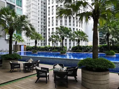 a courtyard with tables and chairs and palm trees at Soho Suites KL City Centre in Kuala Lumpur