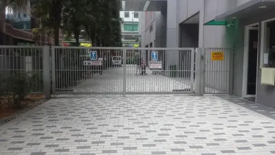 a gate with a person walking into a building at Soho Suites KL City Centre in Kuala Lumpur