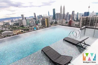 a swimming pool with two chairs and a city skyline at Expressionz KLCC by Wodages in Kuala Lumpur