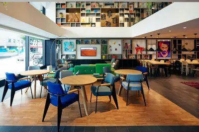 a restaurant with wooden tables and blue chairs at citizenM Kuala Lumpur in Kuala Lumpur