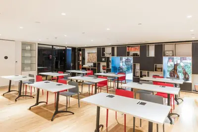 a classroom with white tables and red chairs at citizenM Kuala Lumpur in Kuala Lumpur