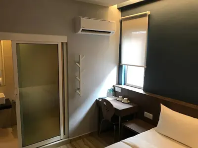 a bedroom with a bed and a desk and a window at Festival Boutique Hotel - Damai Complex in Kuala Lumpur