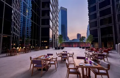 a patio with tables and chairs and buildings at Pavilion Hotel Kuala Lumpur Managed by Banyan Tree in Kuala Lumpur