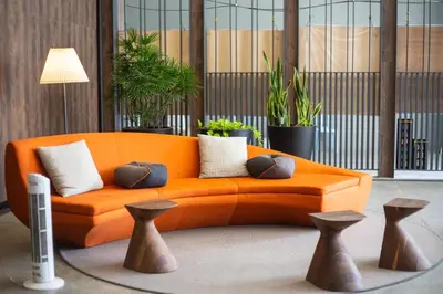 an orange couch in a room with plants at The Mews KLCC by Plush in Kuala Lumpur