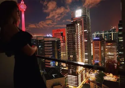 a woman looking at a city skyline at night at Perfect Location@ Heart of KL City Centre next to Metro MRT in Kuala Lumpur
